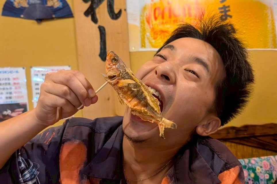 沖縄の魚の唐揚げにかぶりつく社員