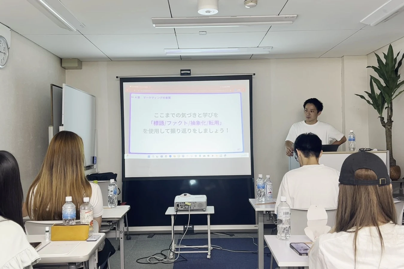 研修会場でスライドを見ながら講義を聞く社員たち
