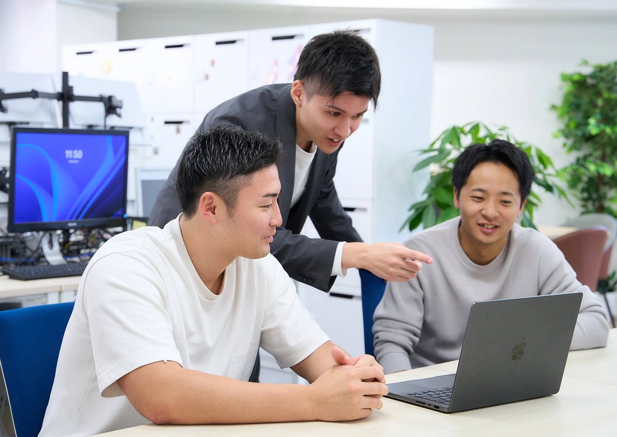先輩社員が後輩にパソコンの画面を指して説明している様子