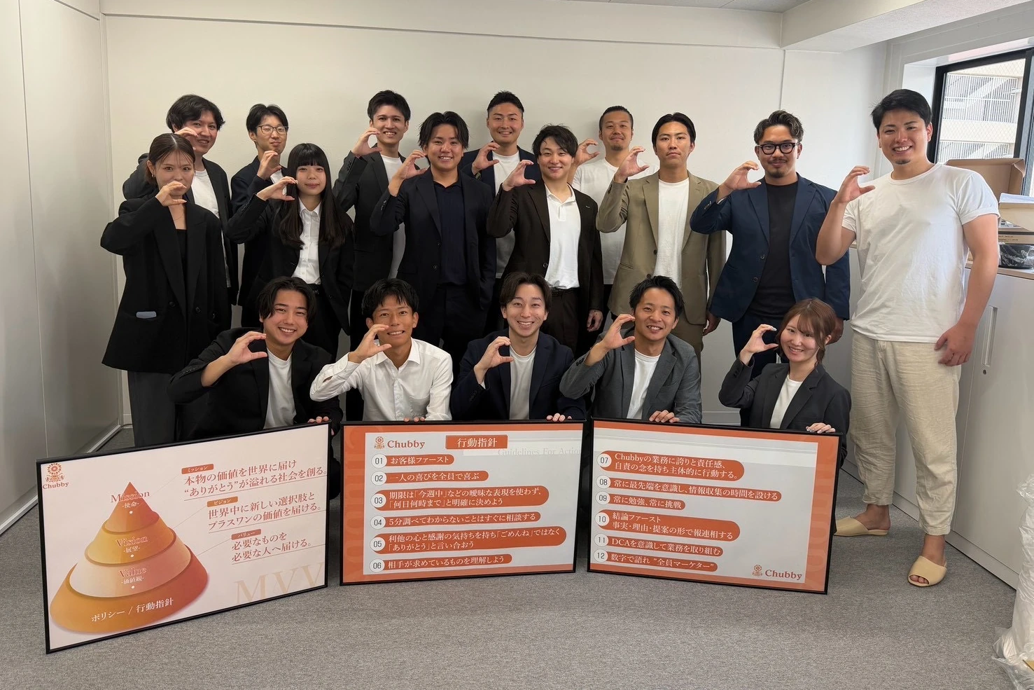 MVVと行動指針のパネルを囲む株式会社Chubbyの社員