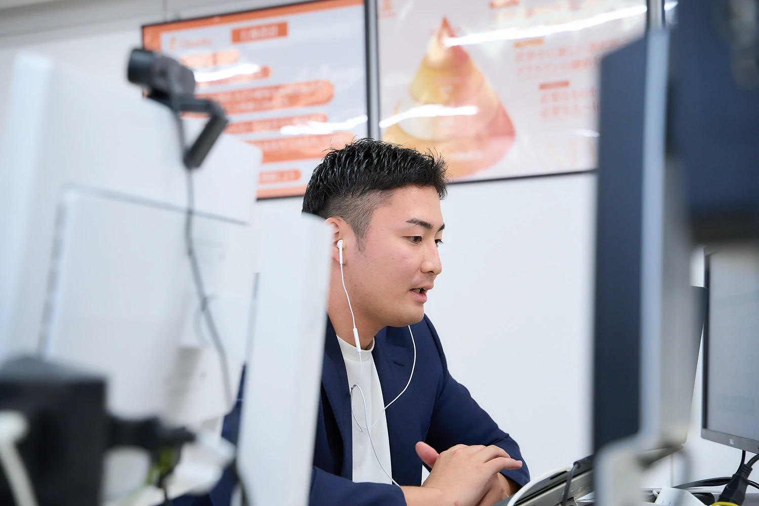 イヤホンをつけてパソコンで作業する社員