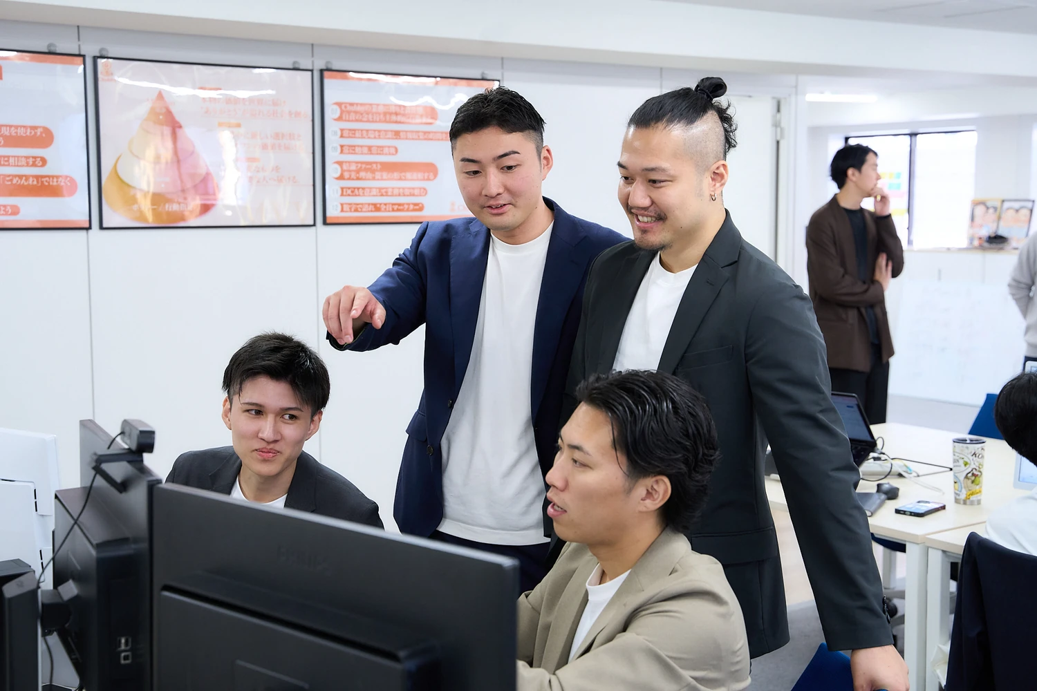画面をのぞき込んで相談する社員たち